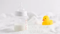 half full baby bottle next to rubber duckie on white surface half full baby bottle next to rubber duckie on white surface