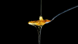 honey dripping onto a spoon black background