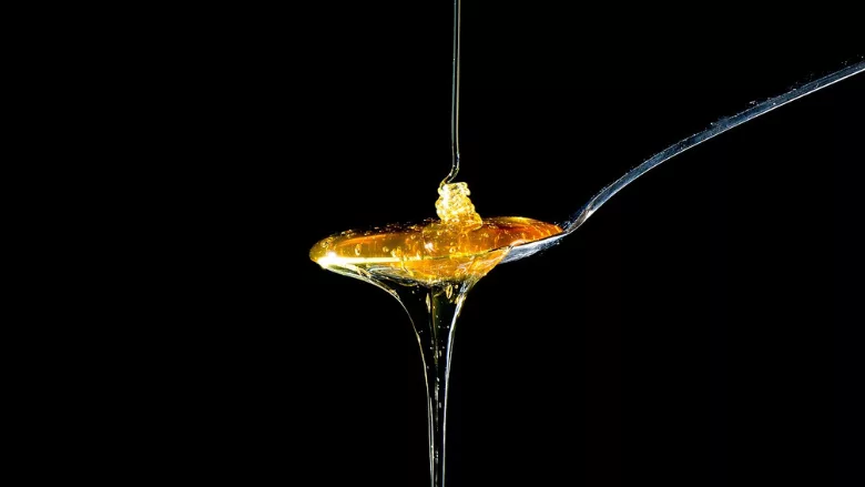 honey dripping onto a spoon black background