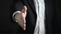 person in suit extending hand for handshake person in suit extending hand for handshake