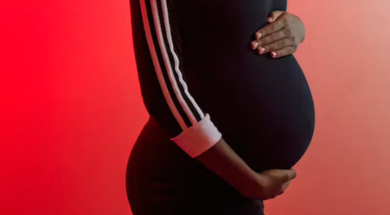 pregnant belly in a black dress against a red background