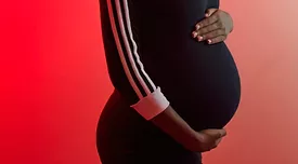 pregnant belly in a black dress against a red background