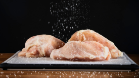 salt falling on raw chicken