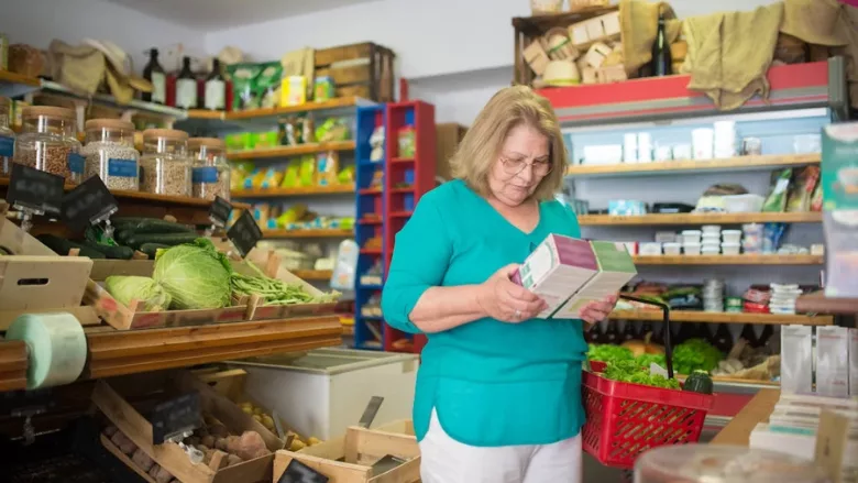 shopper looking at labels on boxed product in grocery store