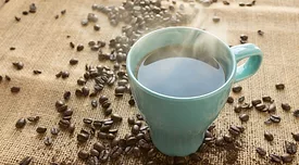steaming mug of coffee with beans in background