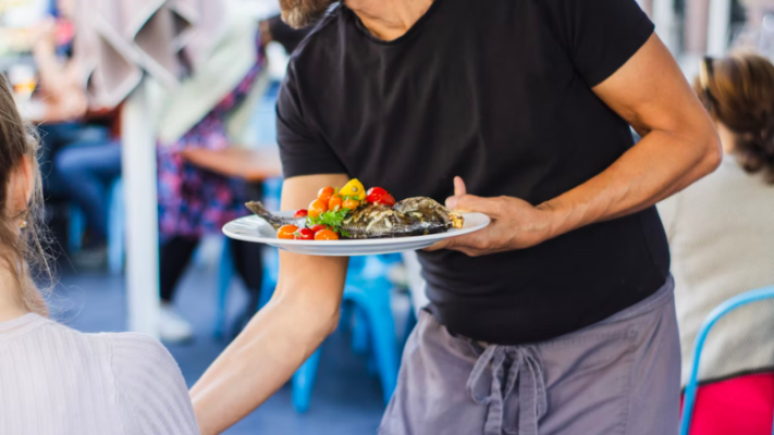waiter in black shirt serving seafood