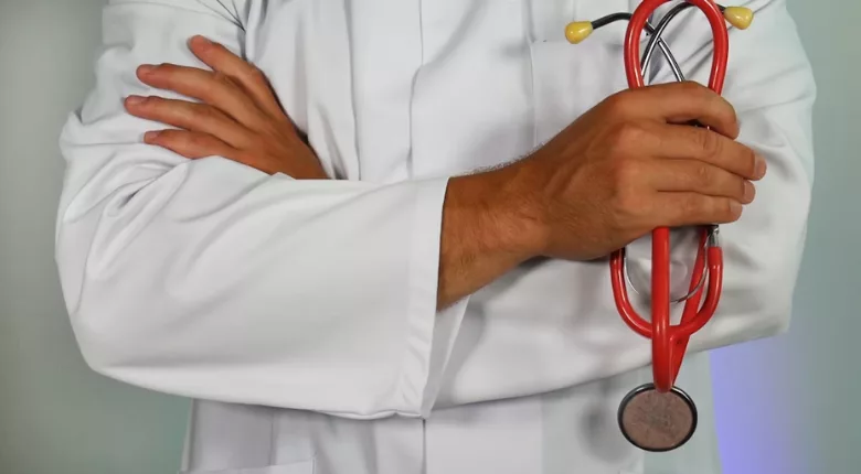 white coat doctor arms crossed holding stethoscope