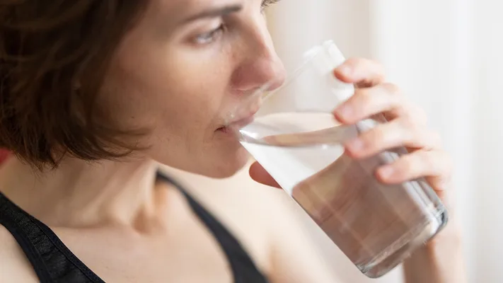 woman drinking glass of water close up from the side
