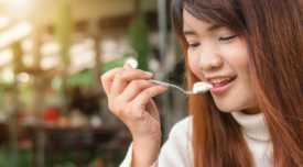 woman eating spoonful of creamy white food