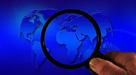 world map with han holding magnifying glass over it