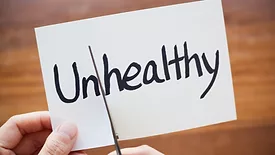 Piece of paper that says unhealthy with un being cut off by scissors