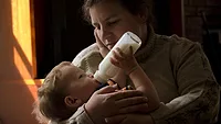 baby eating bottle cuddling mom.png baby eating bottle