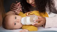 baby drinking bottle with mom