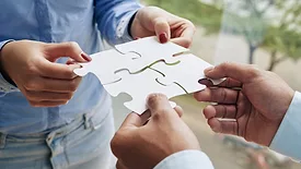business people putting puzzle pieces together representing collaboration