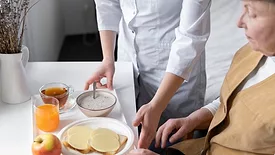 elderly woman being served meal on a tray