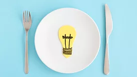 lightbulb on a plate next to fork and knife representing food innovation ideas