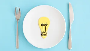 lightbulb on a plate next to fork and knife representing food innovation ideas