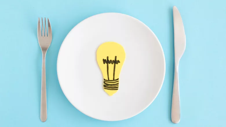 lightbulb on a plate next to fork and knife representing food innovation ideas
