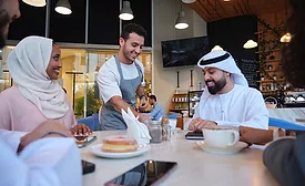 man serving couple wearing traditional garments in cafe