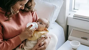mom givingbaby a bottle.png baby eating bottle