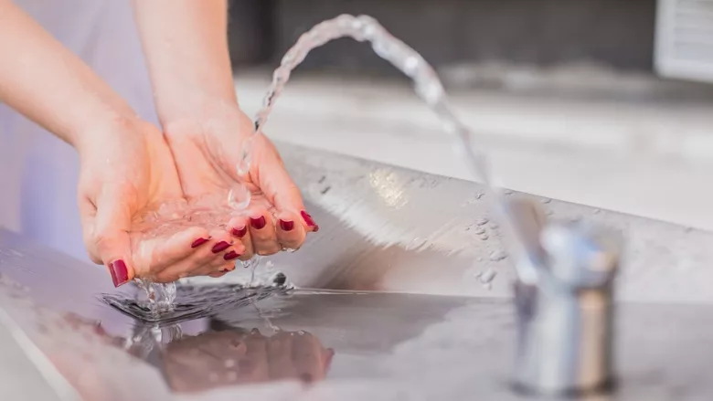 person catching water from drinking fountain with hands