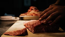 raw meat being cut dark lighting