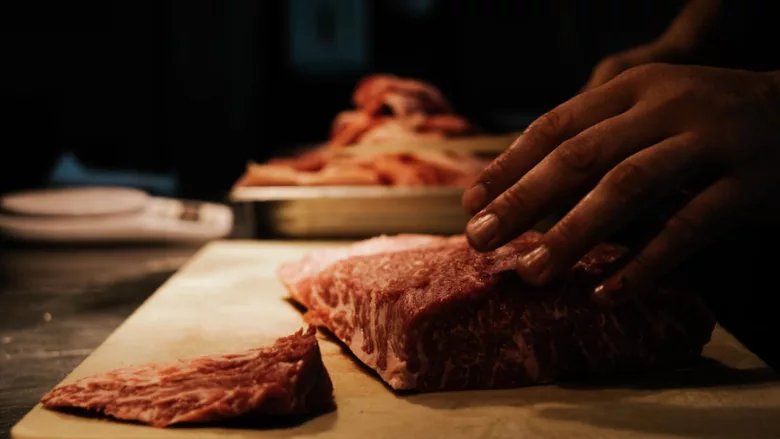raw meat being cut dark lighting