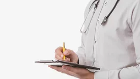 white coat doctor writing on clipboard