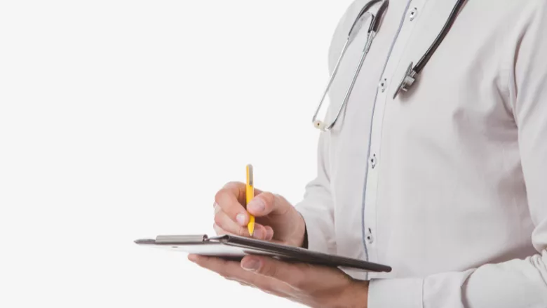 white coat doctor writing on clipboard