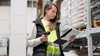 woman in warehouse with scanner device and clipboard