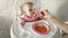 baby being fed puree in high chair