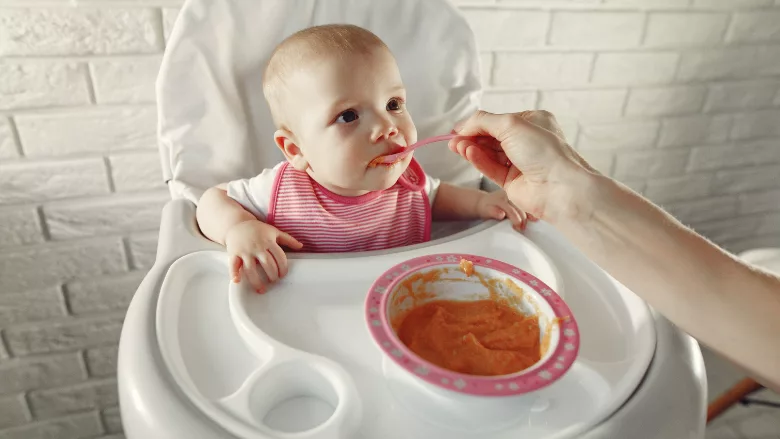 baby being fed puree in high chair