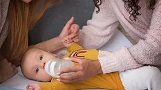 baby having a bottle_freepik via magnific.png baby having a bottle fed by his moms