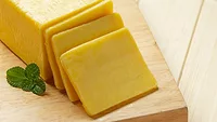 cheddar cheese sliced on wooden cutting board