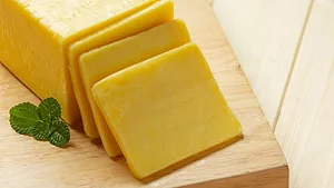 cheddar cheese sliced on wooden cutting board