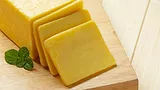 cheddar cheese sliced on wooden cutting board