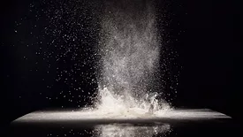 cloud of flour spreading into the air against a black background