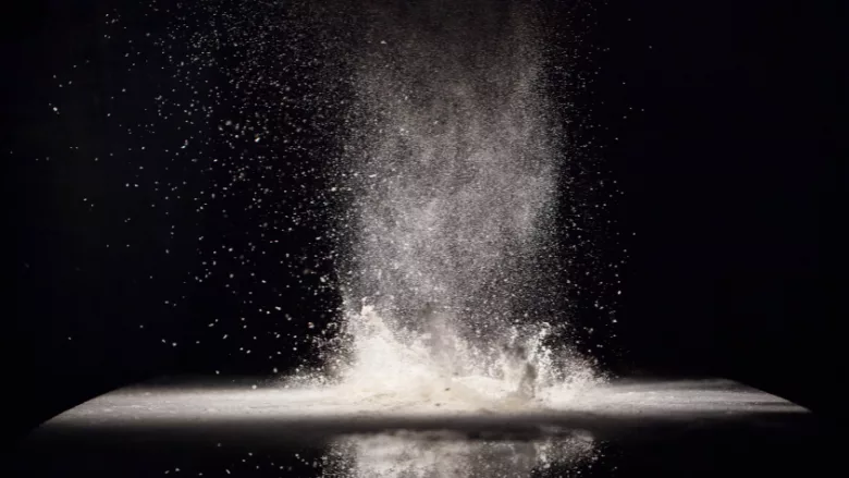 cloud of flour spreading into the air against a black background