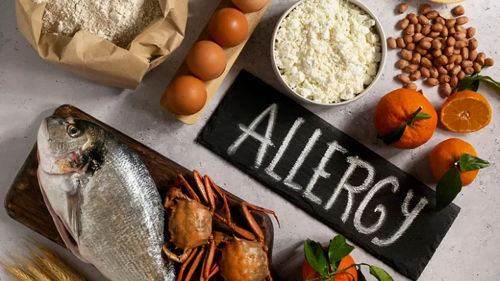 common food allergens with ALLERGY written on table_Freepik via Magnific.png common food allergens and the word ALLERGY