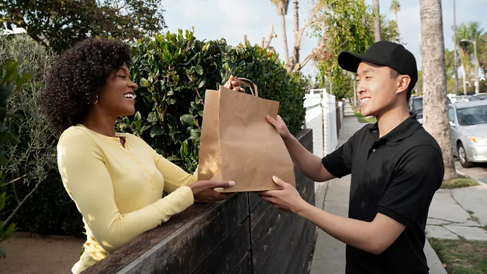 courier delivering food to woman_freepik.png smiling man delivering food to smiling woman