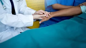doctor holding patient's hand at bedside
