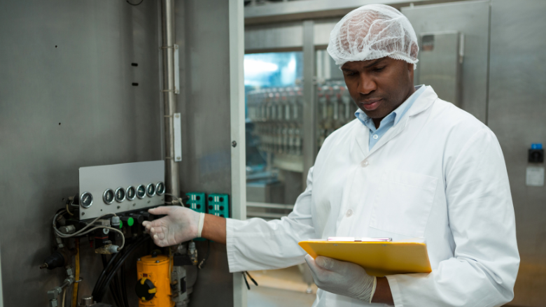 food factory inspector looking at cipboard checking machinery