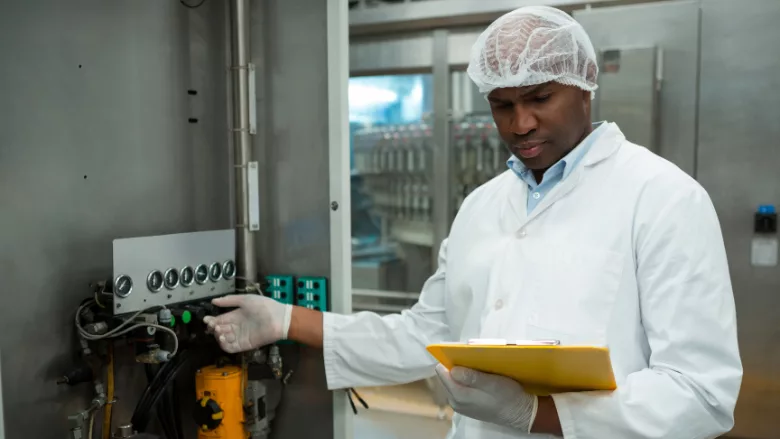 food factory inspector looking at cipboard checking machinery