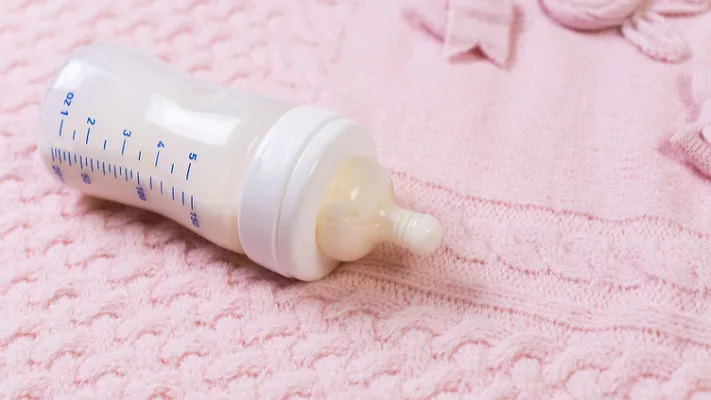 full baby bottle on a blanket_fabrikasimf via Magnific.png full baby bottle on a pink blanket
