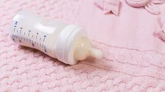 full baby bottle on a pink blanket