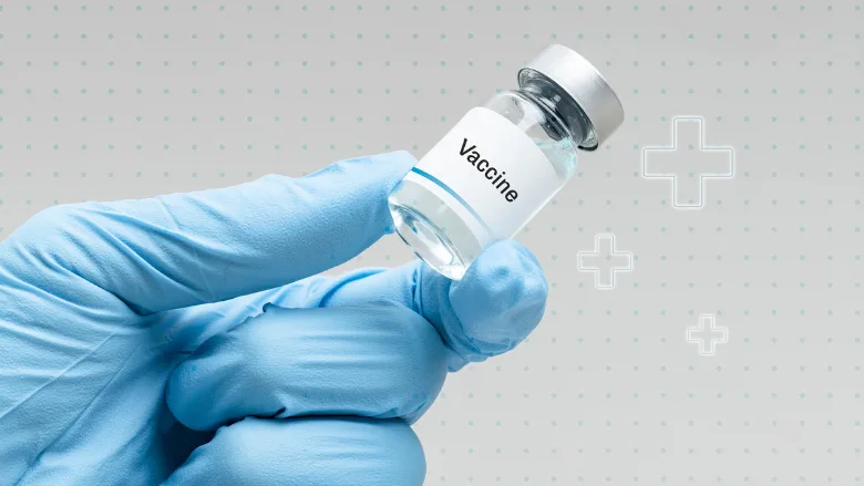 hand wearing blue medical glove holding a vaccine vial