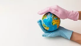 gloved hands of healthcare professionals holding mini world globe