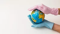 gloved hands of healthcare professionals holding mini world globe