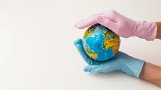 gloved hands of healthcare professionals holding mini world globe