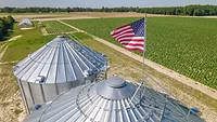 grain silos with US flag on top overlooking field of crops_Mark Stebnicki via Pexels.png grain silos with US flag on top overlooking field of crops